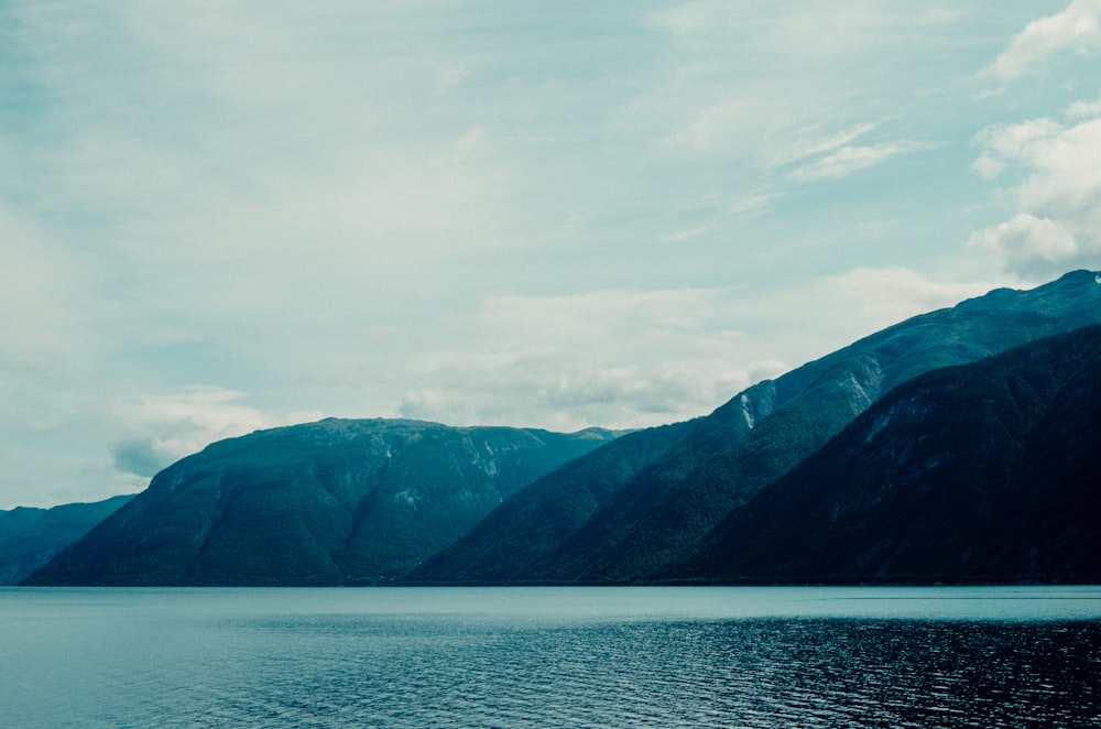 body of water near mountain during daytime