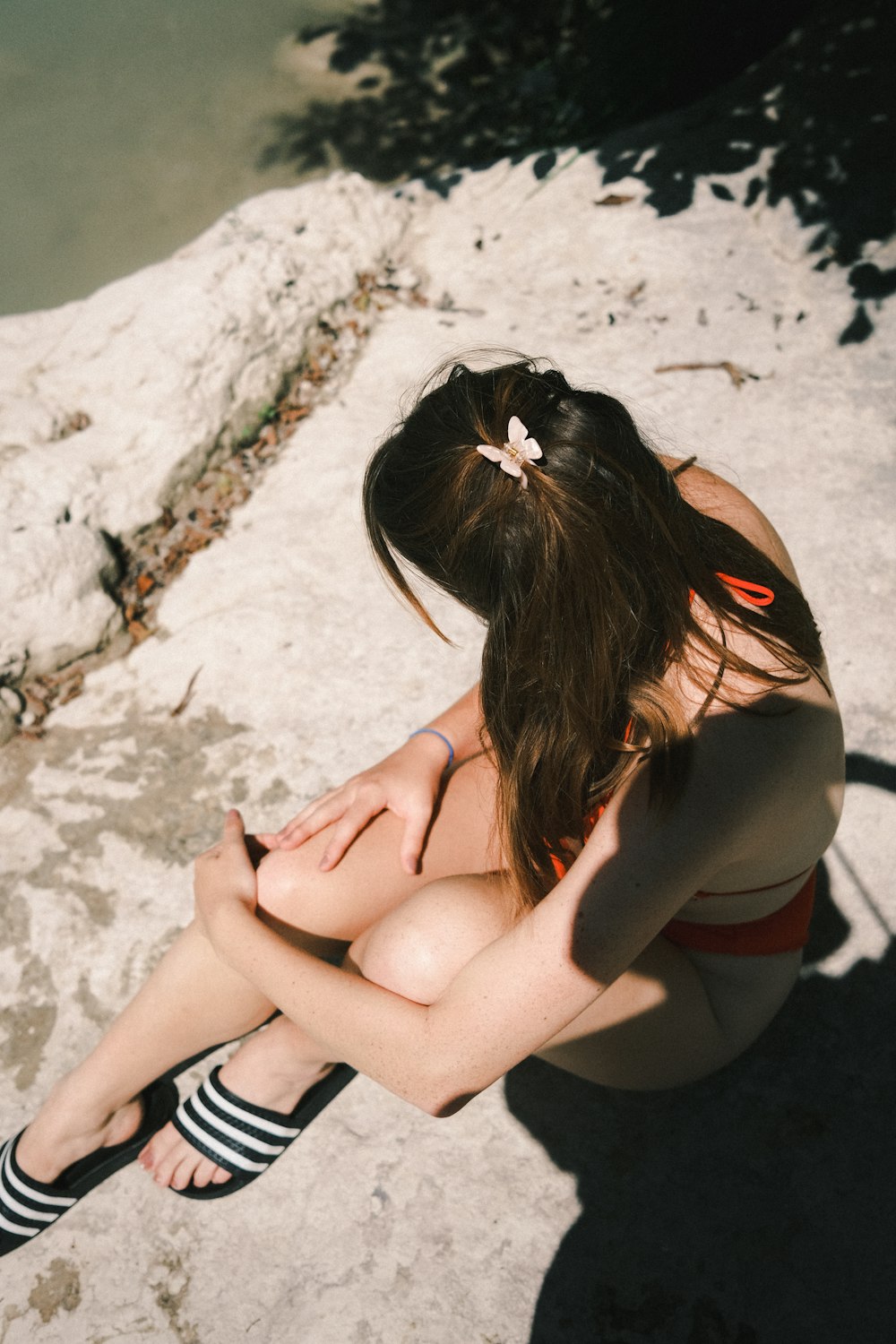 woman in black brassiere and panty sitting on white sand during daytime