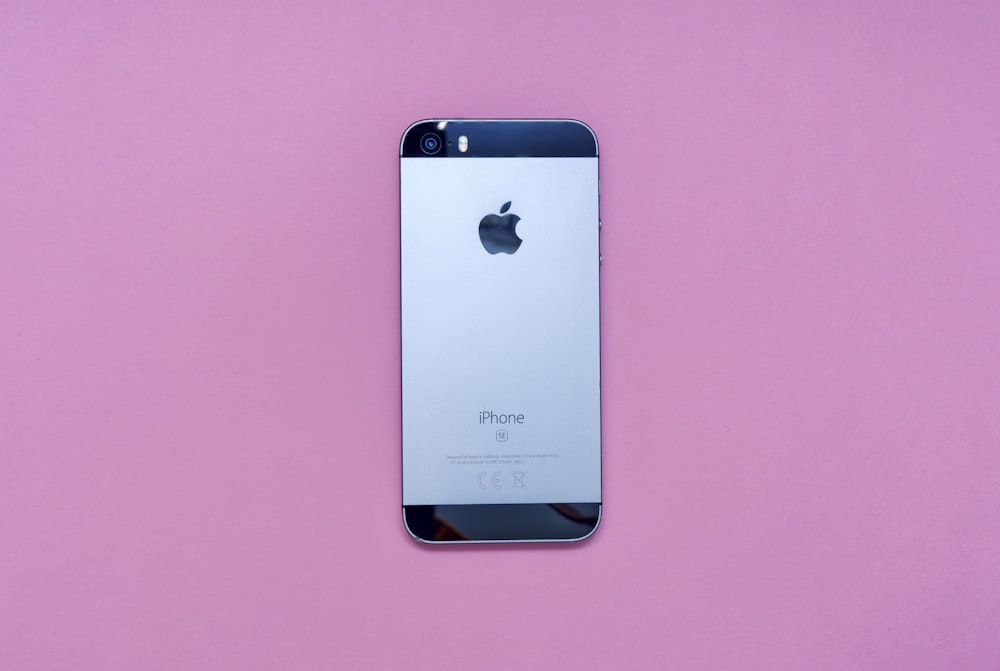 an iphone is sitting on a pink surface