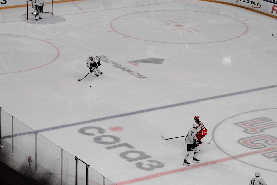 man in white and black ice hockey jersey riding on white and red hockey board