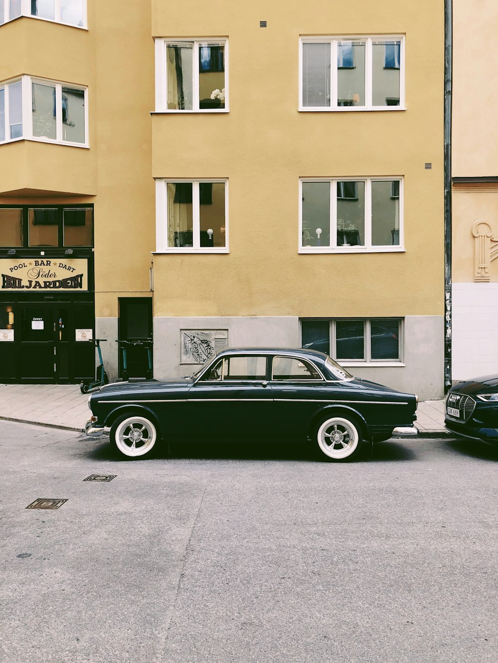 black car parked beside brown concrete building during daytime