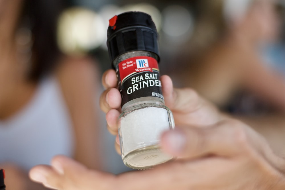 a person holding a bottle of clear sand in their hand