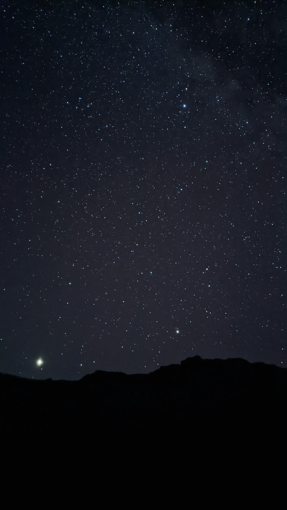 silhouette of mountain under starry night