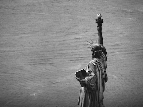statue of a woman holding a flower in grayscale photography