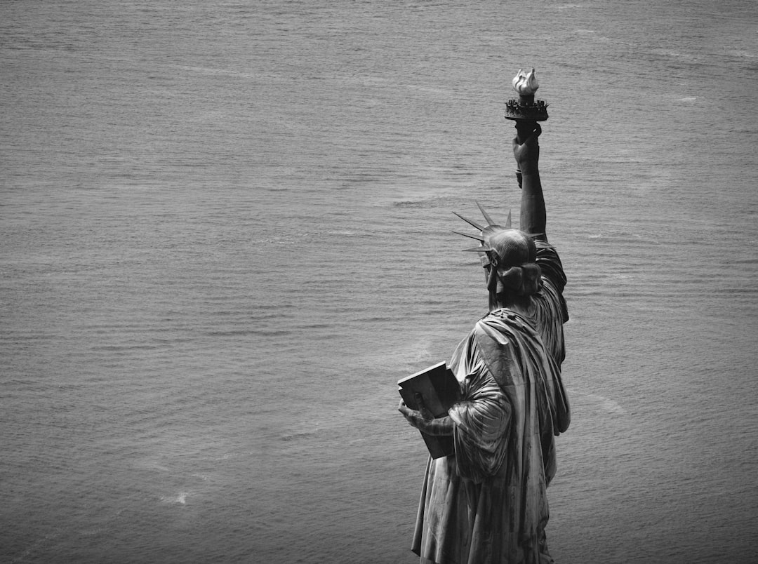 statue of a woman holding a flower in grayscale photography