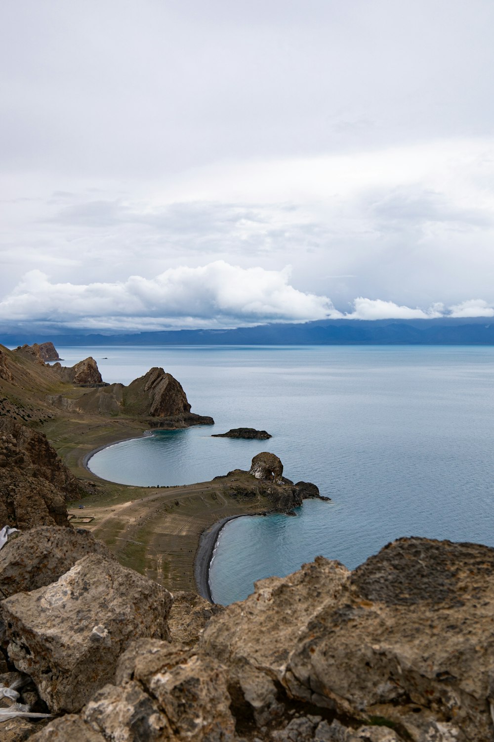 mar azul junto a la montaña marrón bajo el cielo azul durante el día