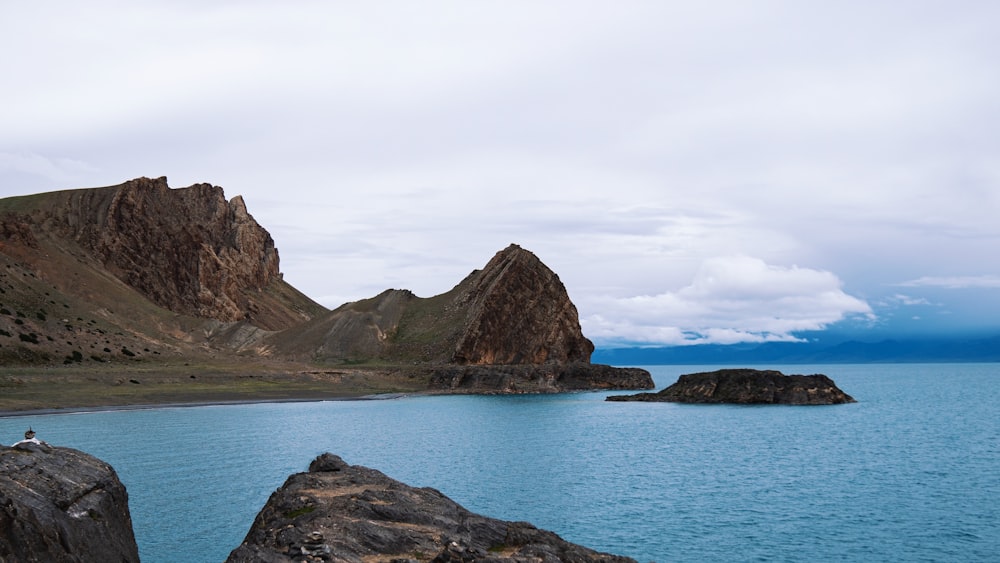 Formación de roca marrón en el mar bajo el cielo blanco durante el día