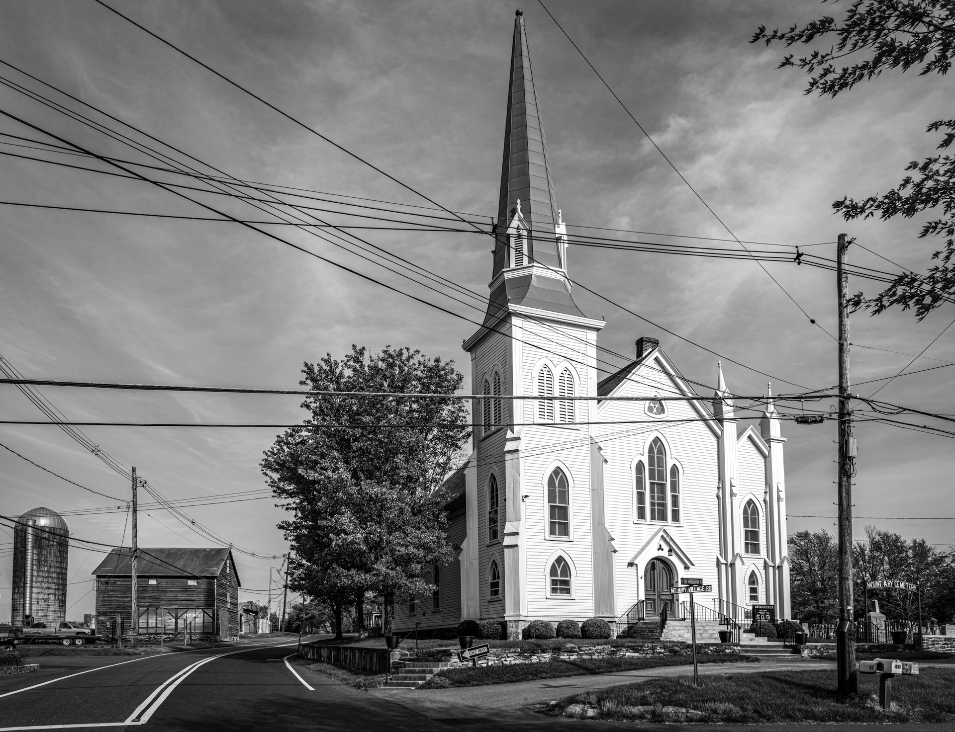 A vintage black-and-white photograph of the church's original wooden structure surrounded by early 20th-century townsfolk.