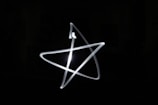 A light painting of a star shape against a dark background. The image captures the smooth, bright white lines in motion, creating a glowing effect.