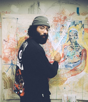 man in black and white sweater standing beside wall with graffiti