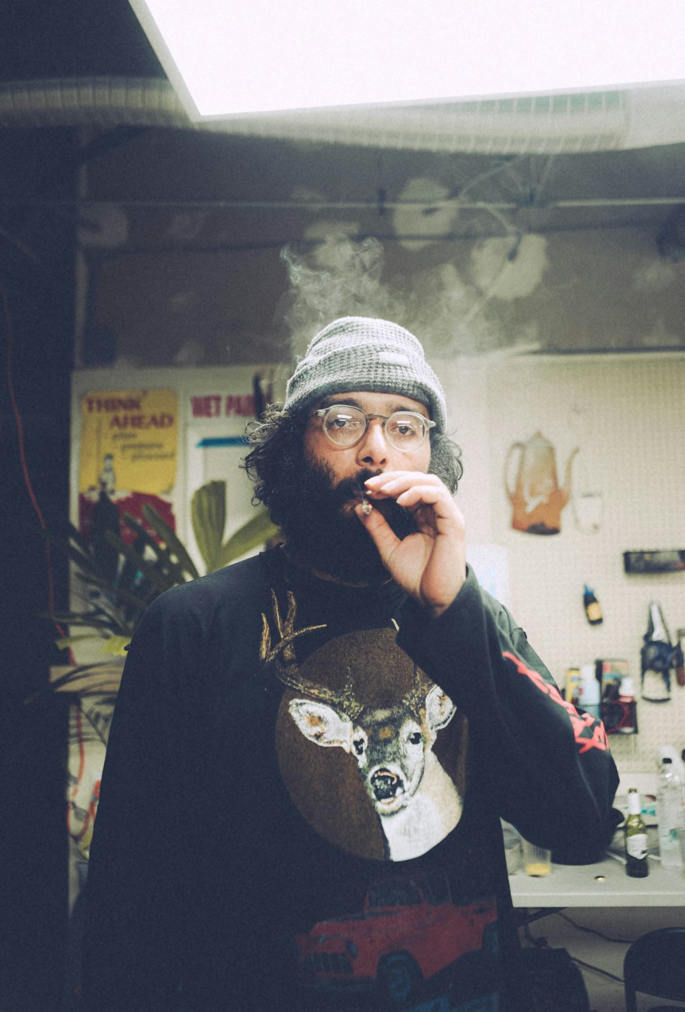 man in black jacket wearing white knit cap smoking cigarette