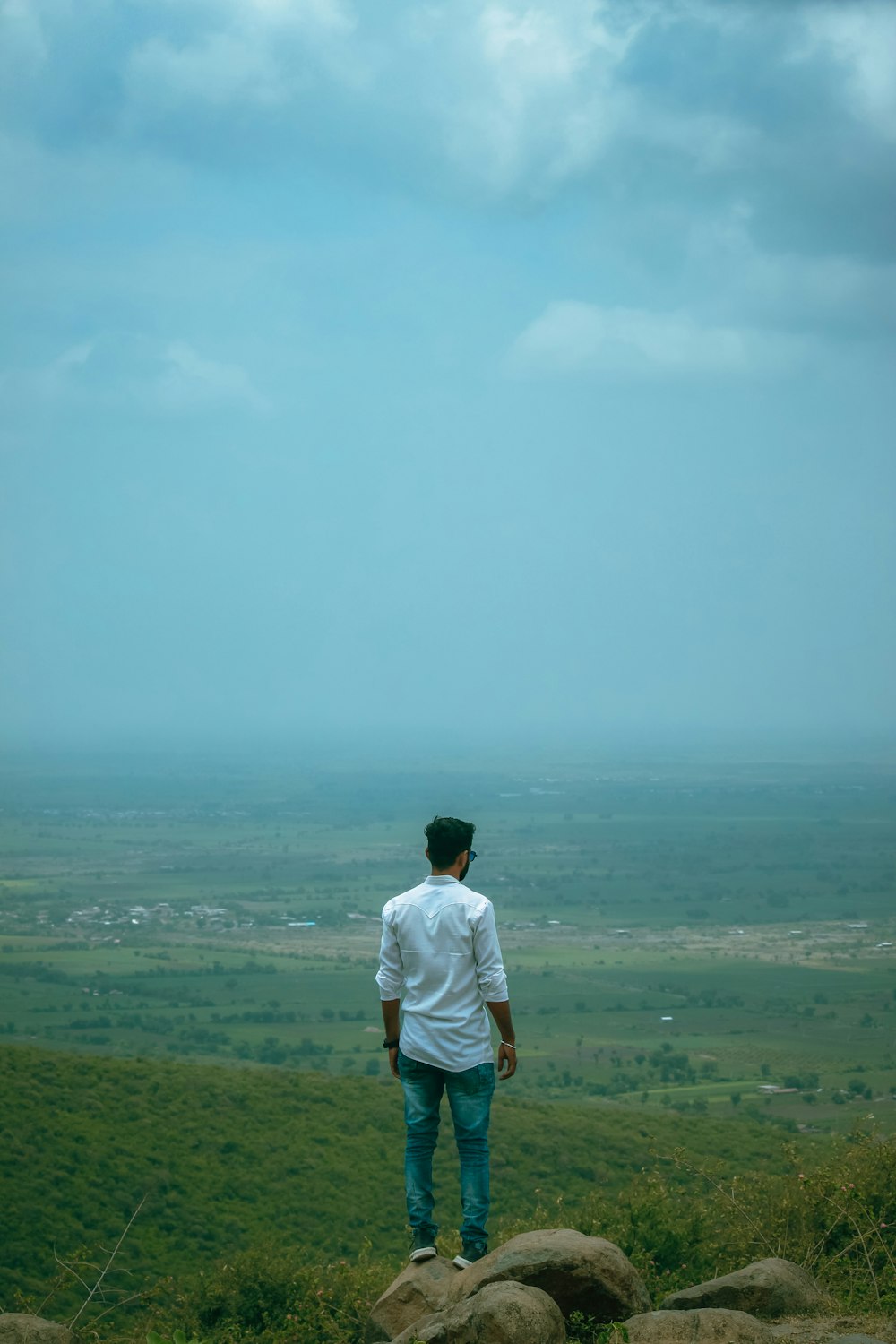 uomo in maglietta bianca in piedi sul campo di erba verde durante il giorno