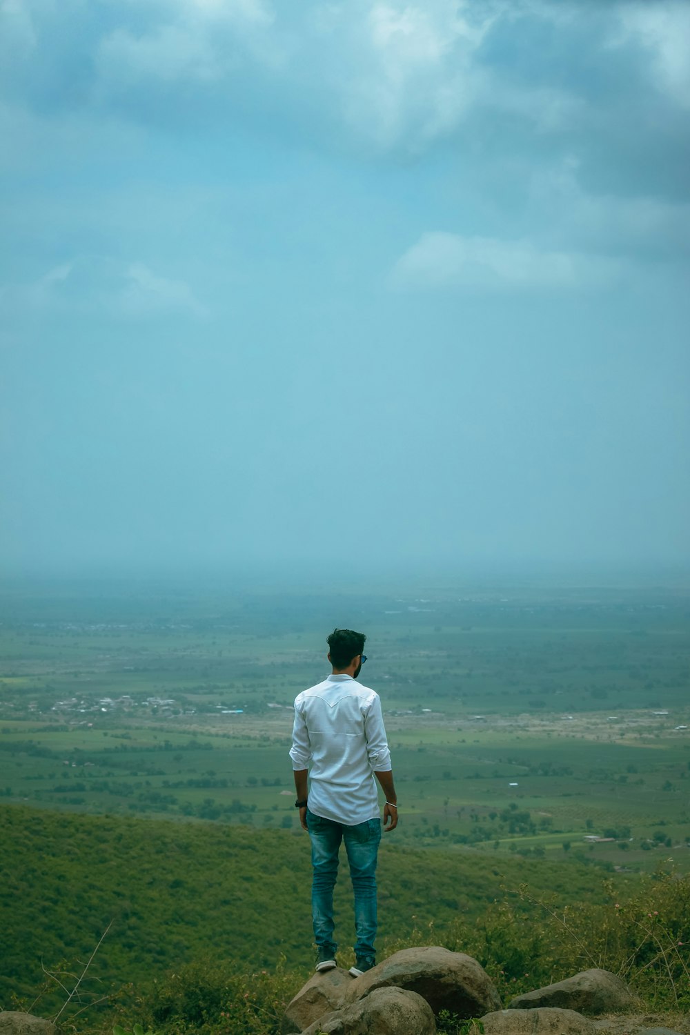 man in white t-shirt standing on green grass field during daytime