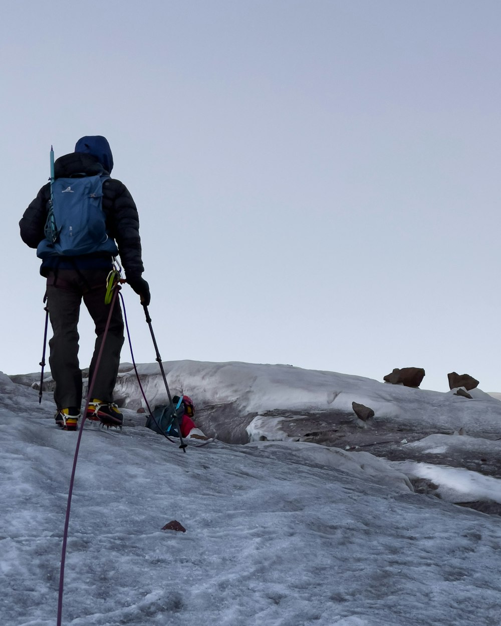 man in blue jacket and black pants holding ski poles on snow covered ground