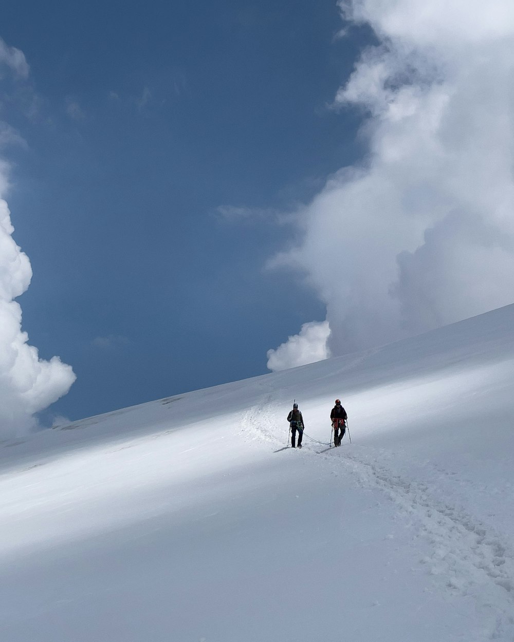 person walking on snow covered field under blue sky during daytime