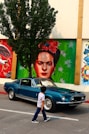 man in blue crew neck shirt standing beside black car