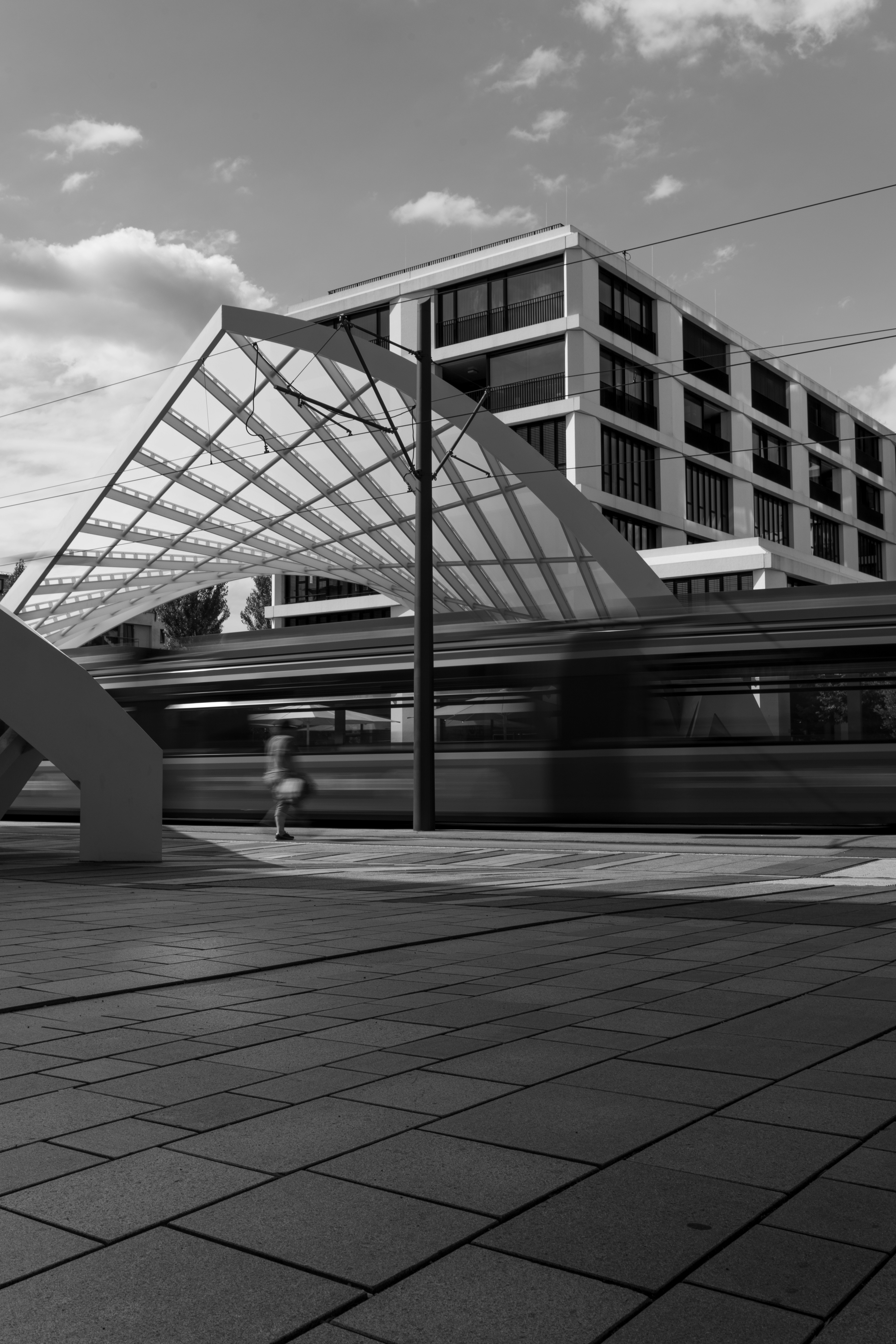 Ein Schwarz-Weiß-Foto eines Zuges, der an einem Gebäude vorbeifährt