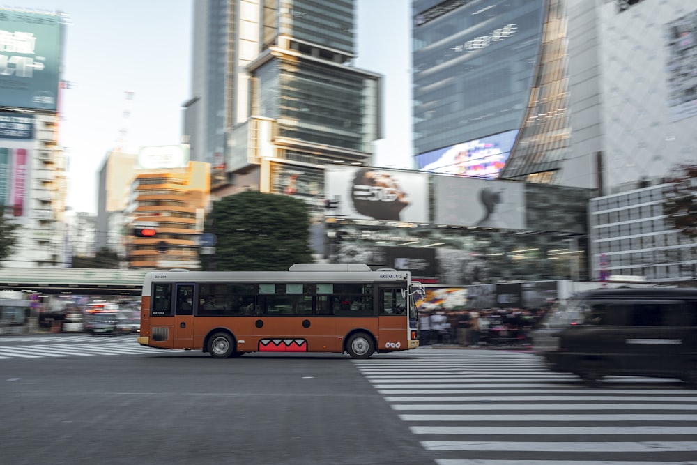 an orange bus driving down a street next to tall buildings