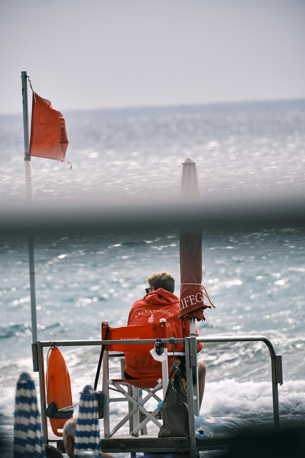 man in orange shirt holding white and red flag on beach during daytime