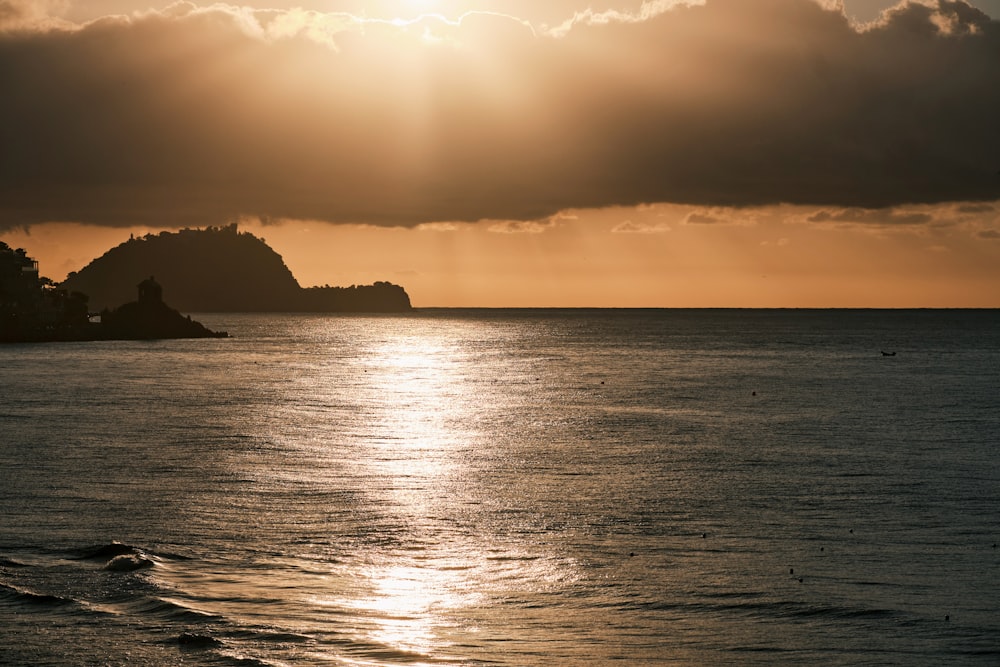 silhouette of mountain beside sea during sunset