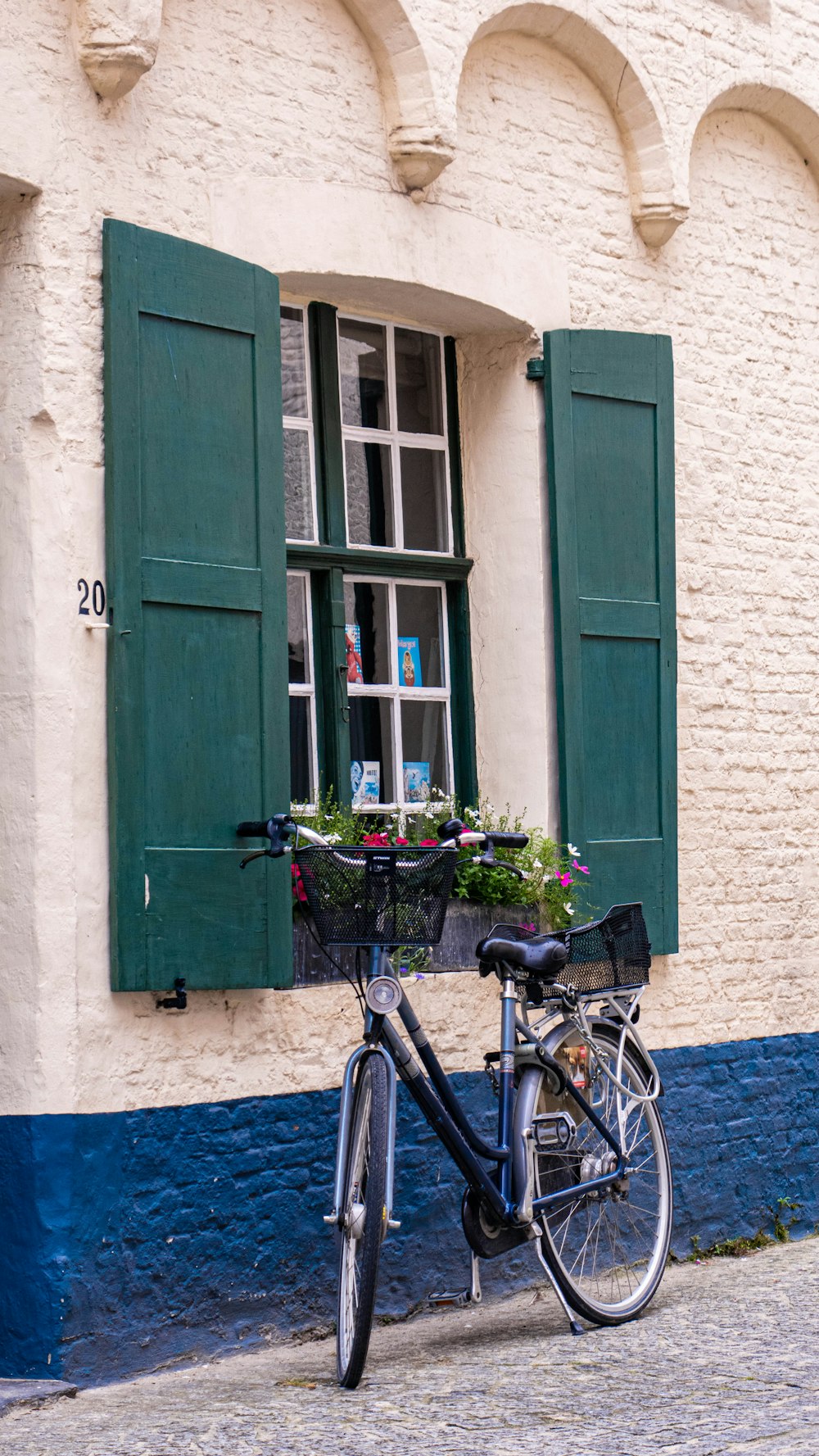 Bicicleta de cercanías en blanco y negro estacionada al lado de un edificio de concreto verde