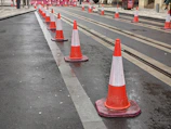 Bright orange traffic cones lined up along a busy Mumbai street.