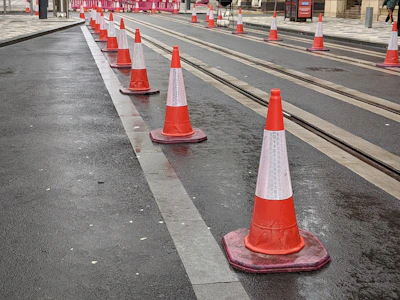 A team member placing traffic cones precisely according to a traffic control plan on a city street.