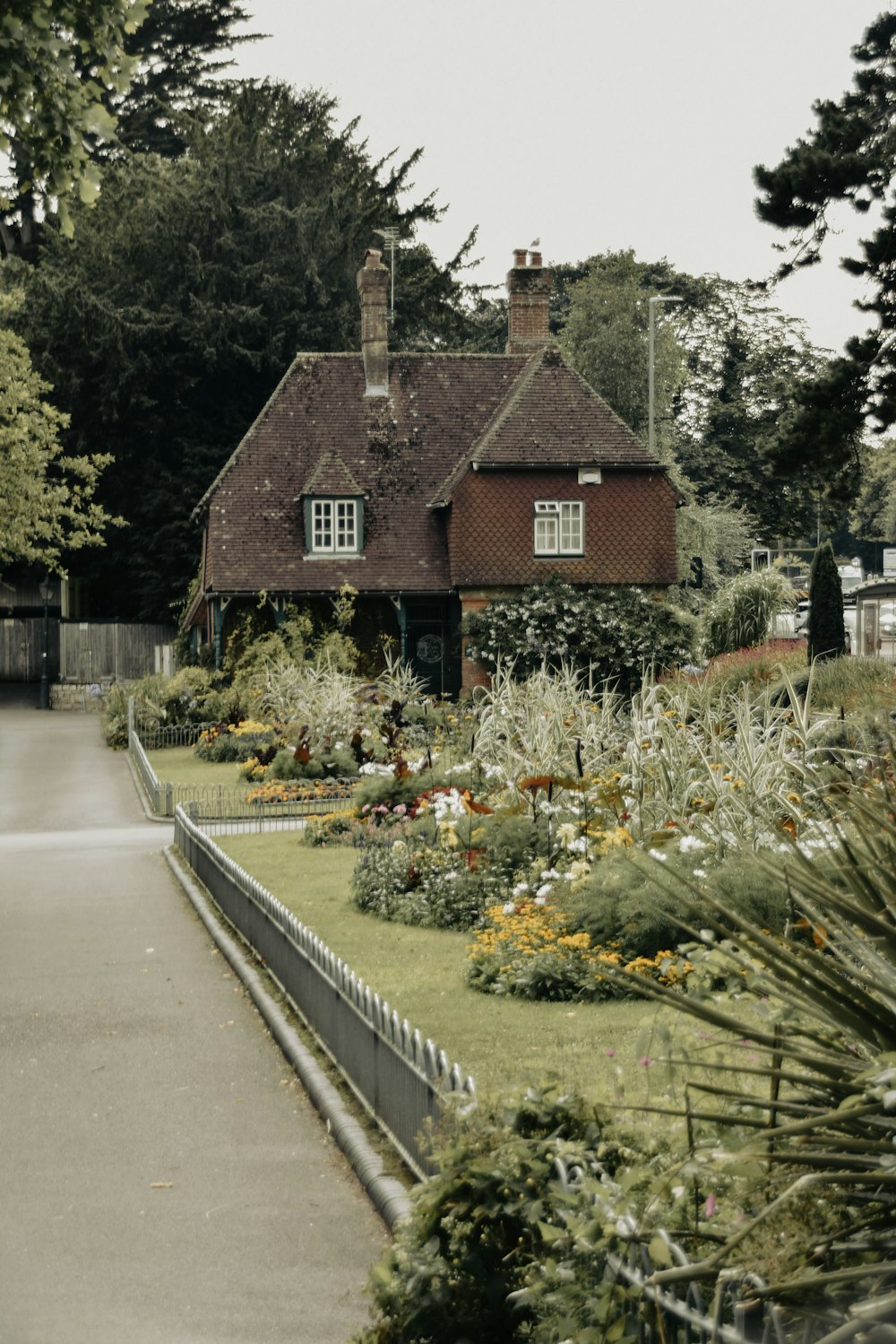 brown and white house beside green trees and plants during daytime