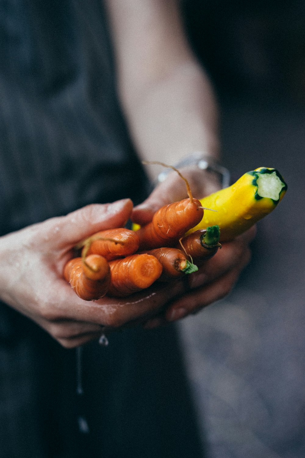 person holding green and orange bell pepper