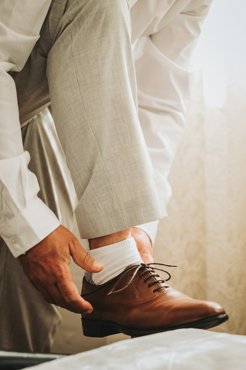 person in gray formal suit jacket wearing brown leather shoes