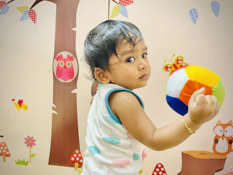 Friendly pediatrician gently examining a toddler with colorful wall decorations in the background.