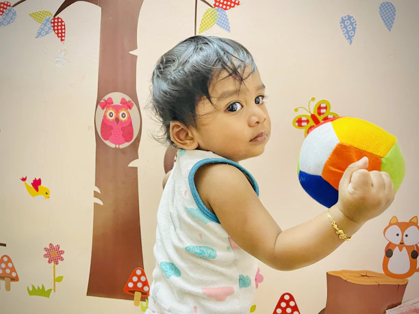 Friendly pediatrician gently examining a toddler with colorful wall decorations in the background.