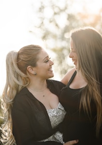 woman in black blazer kissing woman in white floral shirt