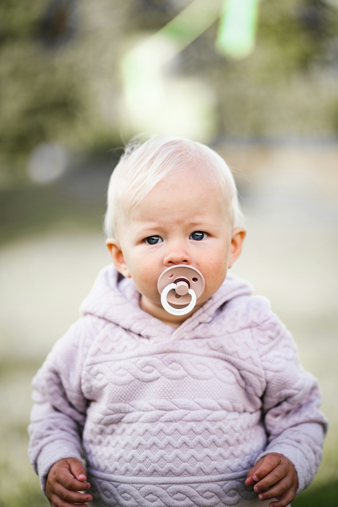 baby in white knit sweater with blue pacifier