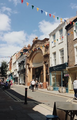 A welcoming historic downtown street scene with charming storefronts and hanging flower baskets on a sunny day.