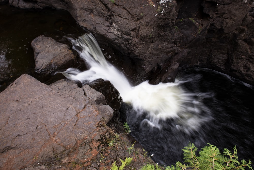 water falls on brown rocky mountain during daytime