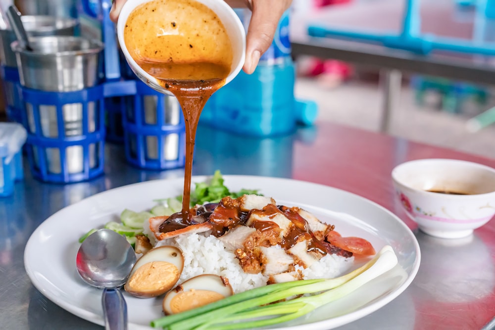 person holding stainless steel spoon and fork on white ceramic plate