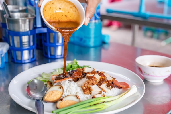 Person holding stainless steel spoon and fork on white ceramic plate