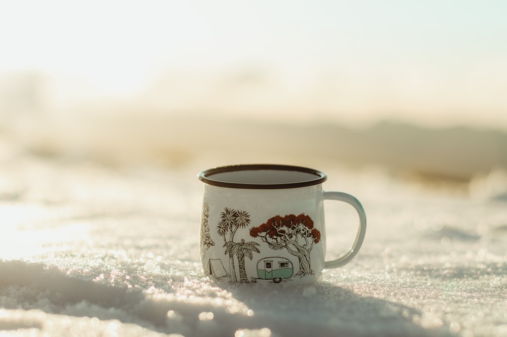 white and black ceramic mug on white snow