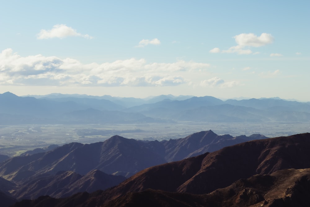 brown and green mountains under white clouds and blue sky during daytime