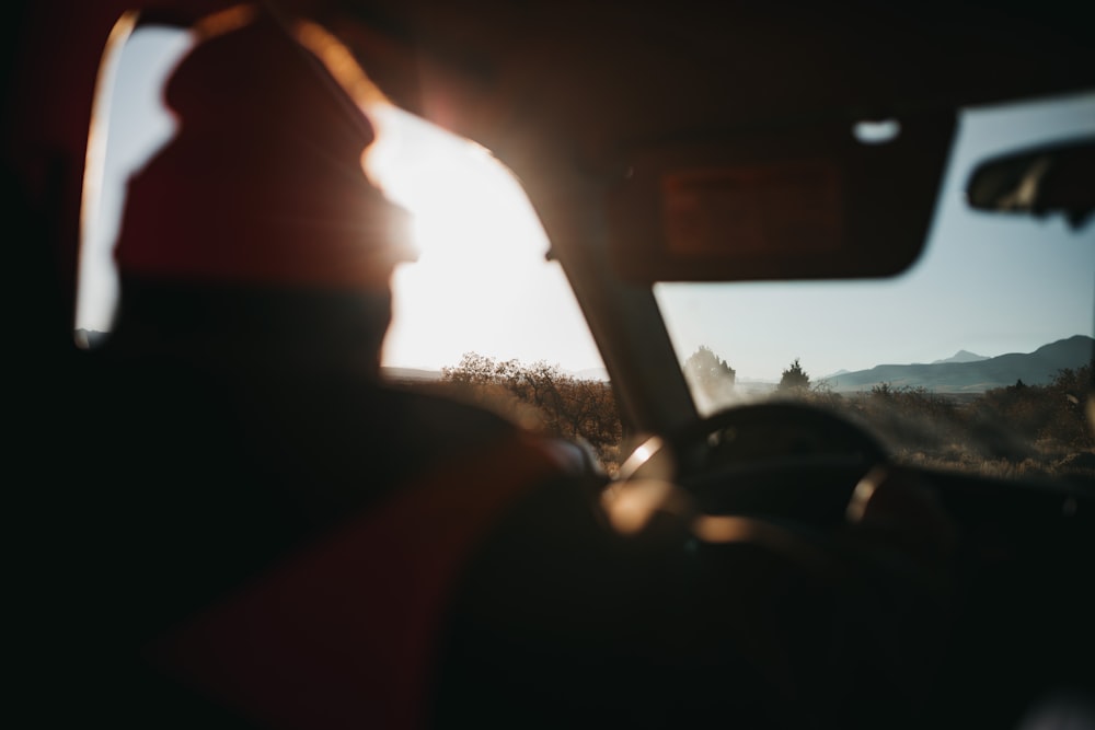 man in red shirt driving car during daytime