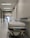A hospital hallway is depicted with a gurney positioned in the foreground. The corridor is clean and well-lit, with signs indicating different departments such as 'GASTROENTEROLOGIE.' Several closed doors and white walls line the hallway, creating a sterile and orderly environment.