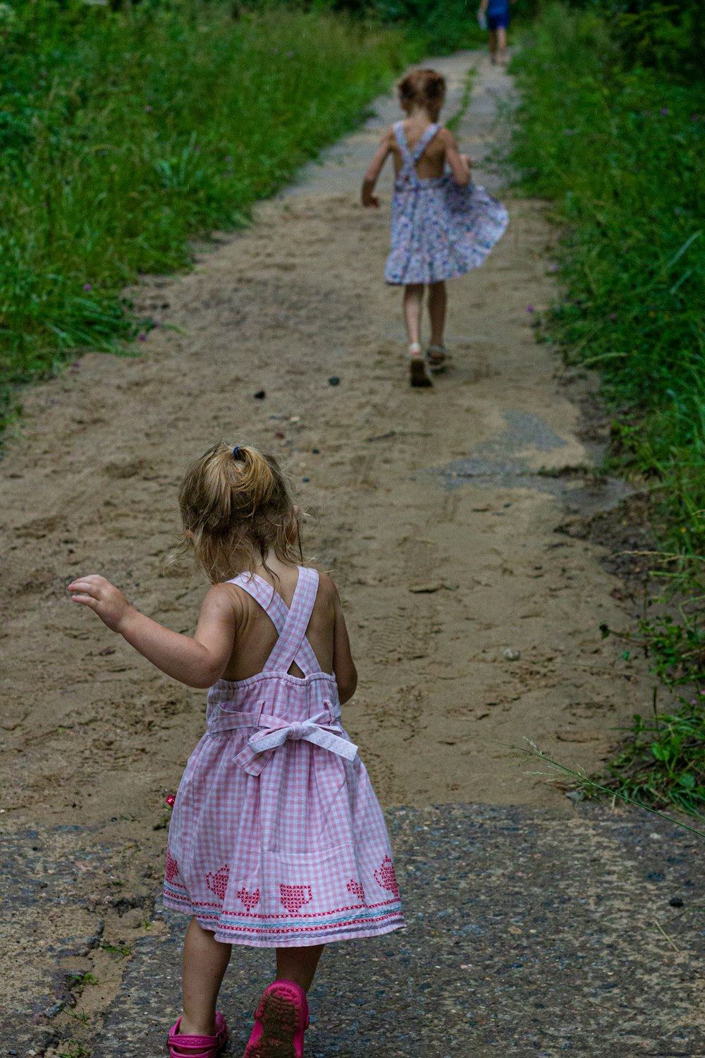 girl in pink and white polka dot dress walking on dirt road during daytime