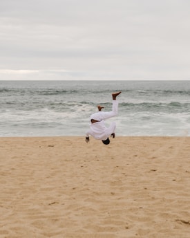 woman in white long sleeve shirt and white pants running on beach during daytime