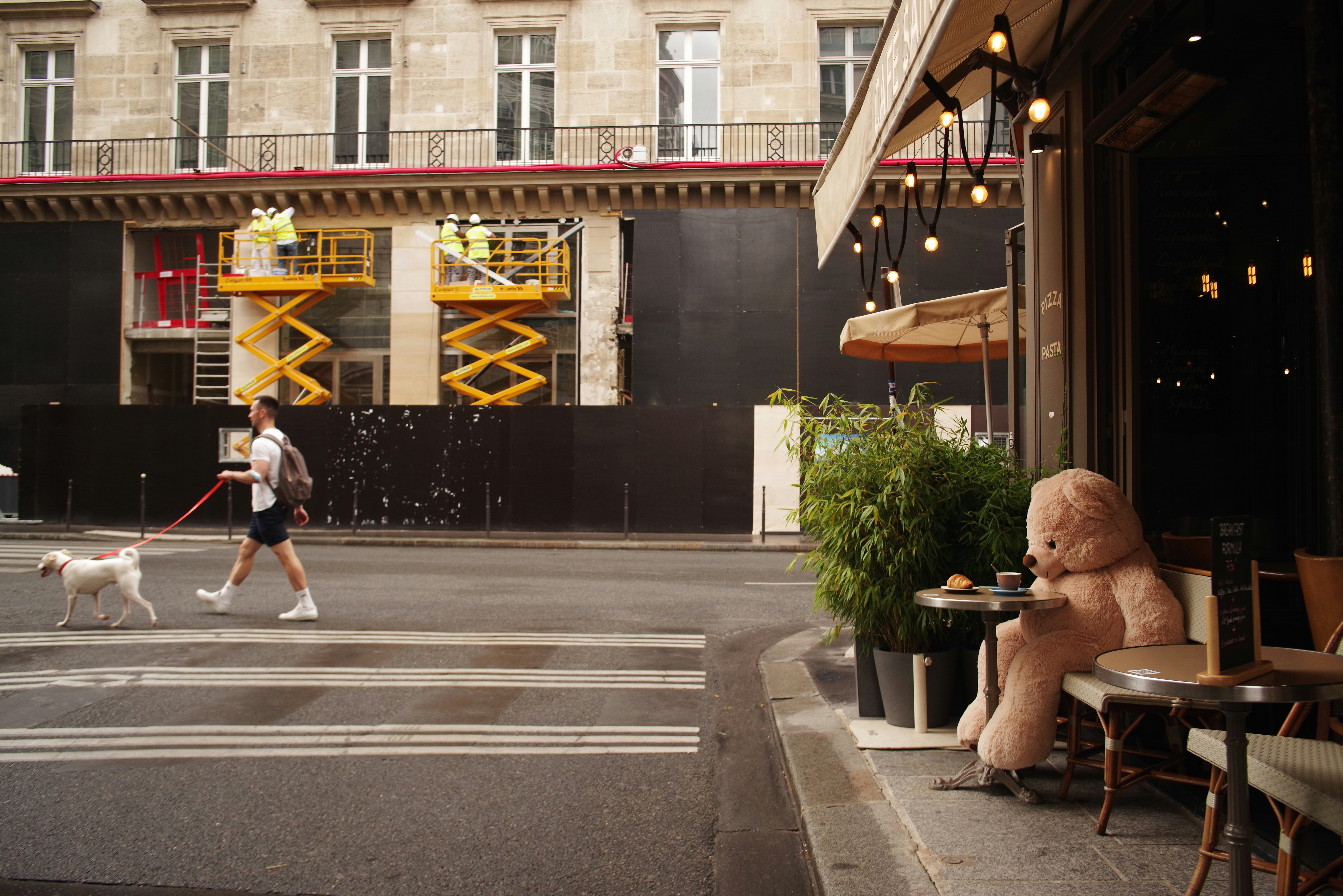 man in black t-shirt and blue denim jeans walking on pedestrian lane during daytime, 