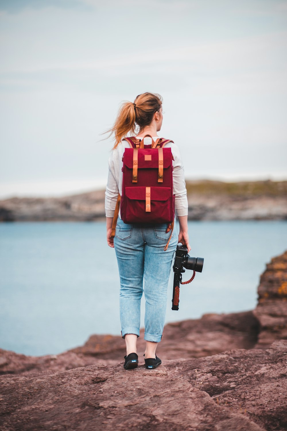 Femme en jean bleu portant un sac à dos rouge et noir debout sur un rocher  près du corps de près de près de près de photo – Photo Vêtements Gratuite  sur