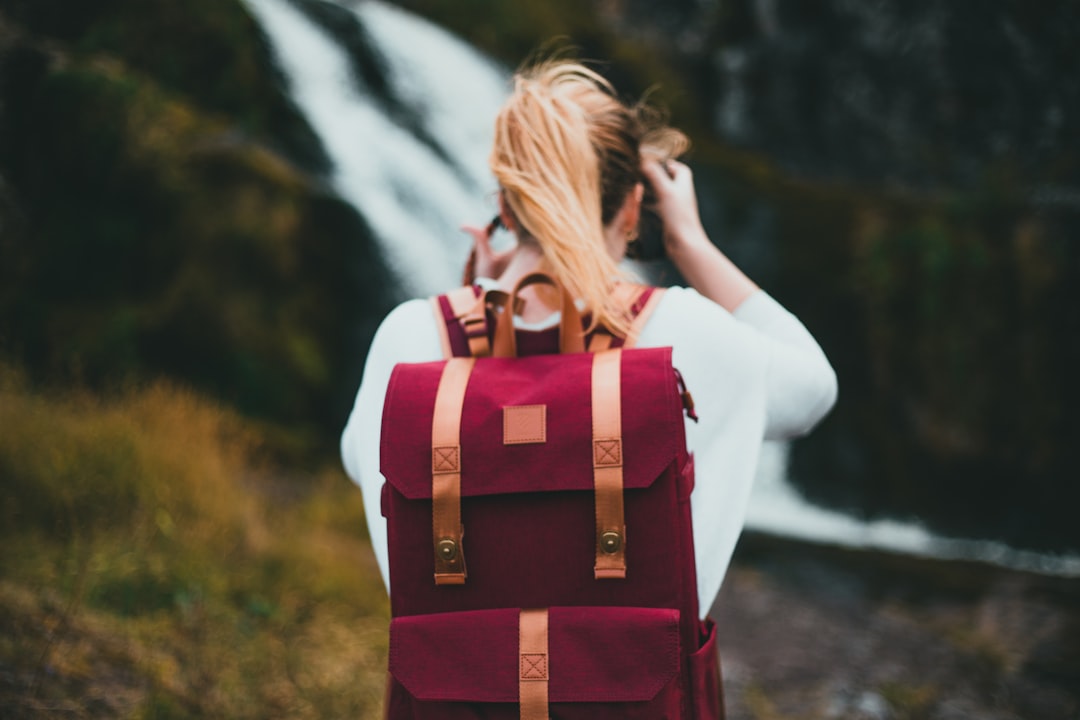 woman in white long sleeve shirt with red and brown backpack