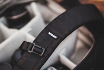 A padded camera bag interior with multiple compartments is visible. The focus is on a black strap with a buckle and a logo tag reading 'incase'. The surrounding compartments contain camera lenses.