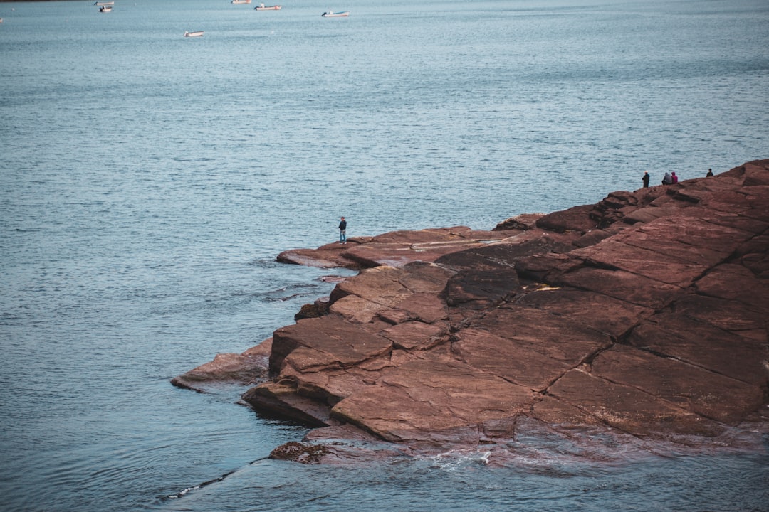 person standing on brown rock formation near body of water during daytime