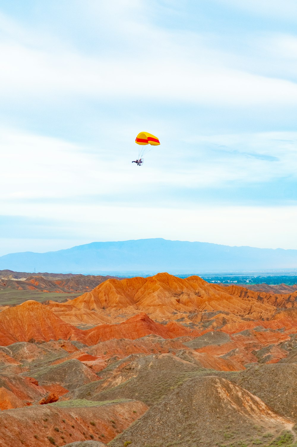 person in red parachute over brown mountains during daytime